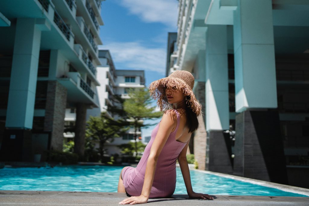 A female influencer sitting on the edge of a pool at a hotel resort. 