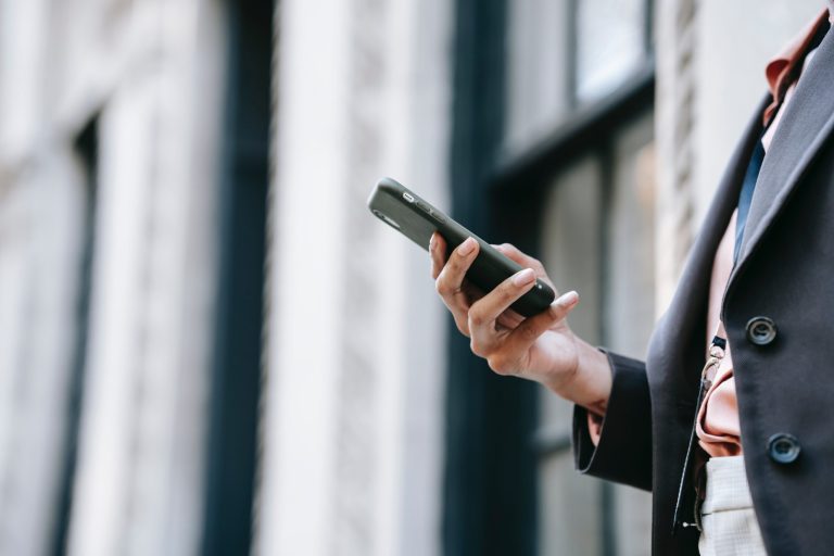 Person on the right side of the frame holding their cell phone looking at social media pages.