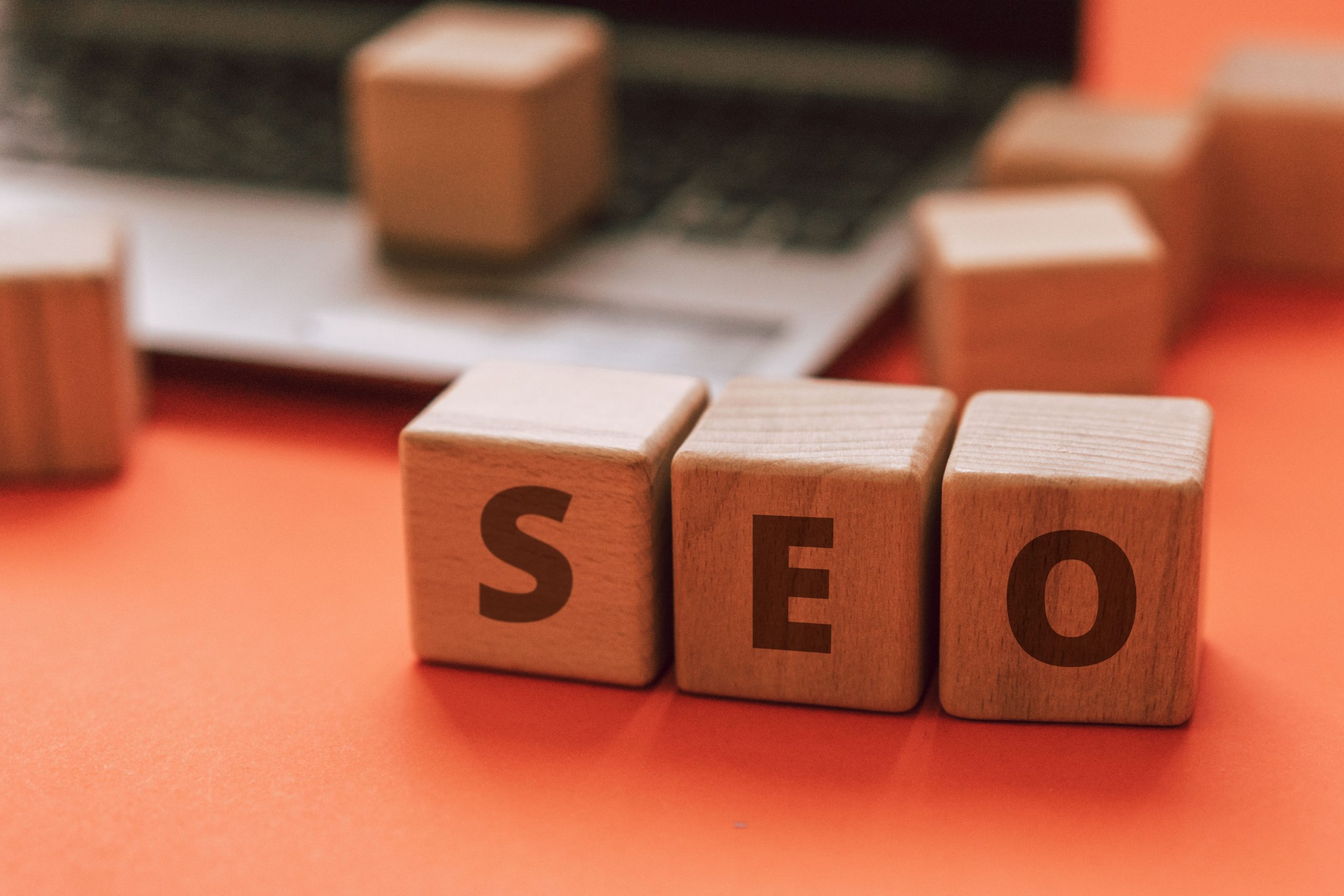 Three blocks that spell out SEO next to a computer on a desk.