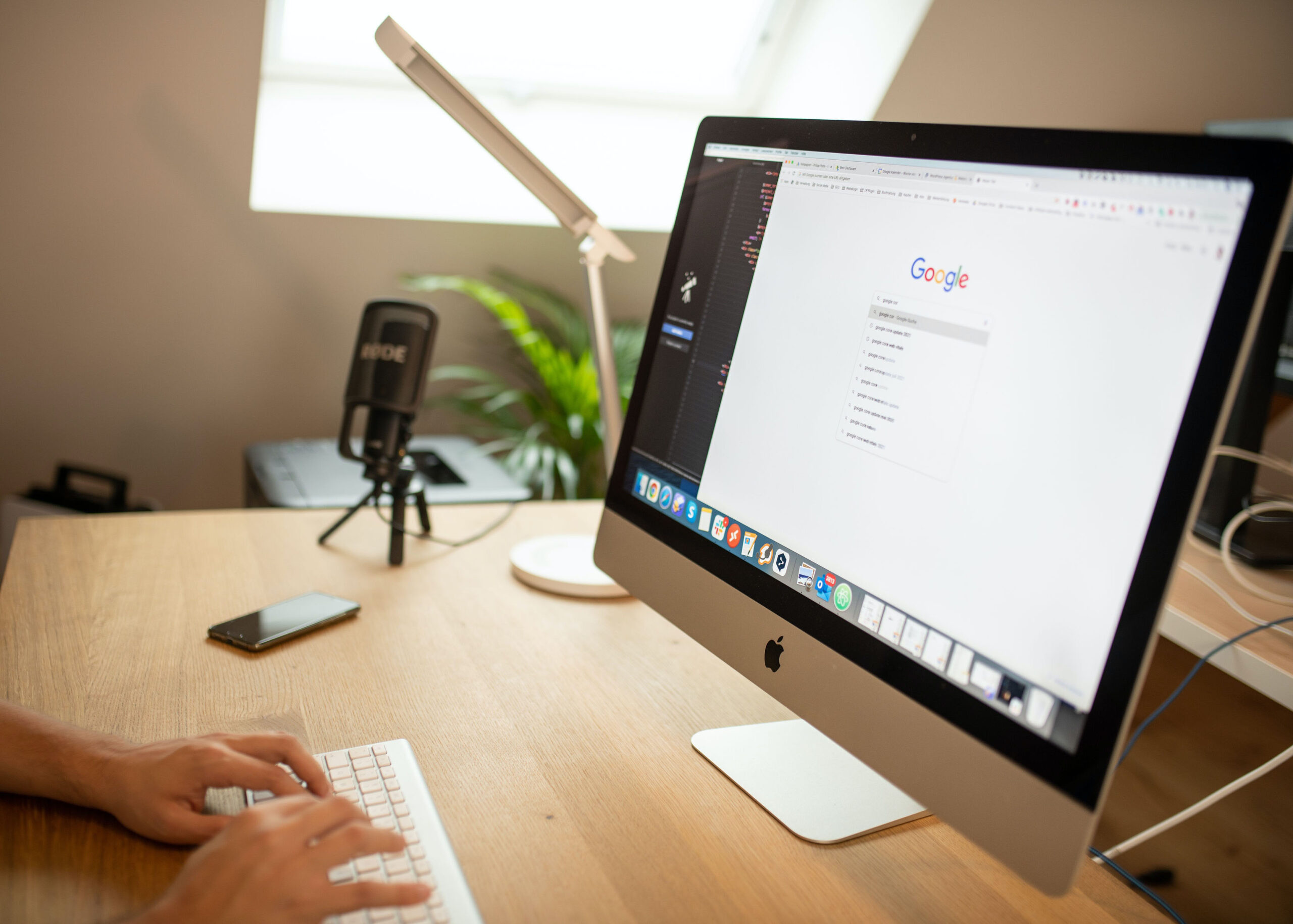 A person about to type something into Google on their computer which sits atop their desk.