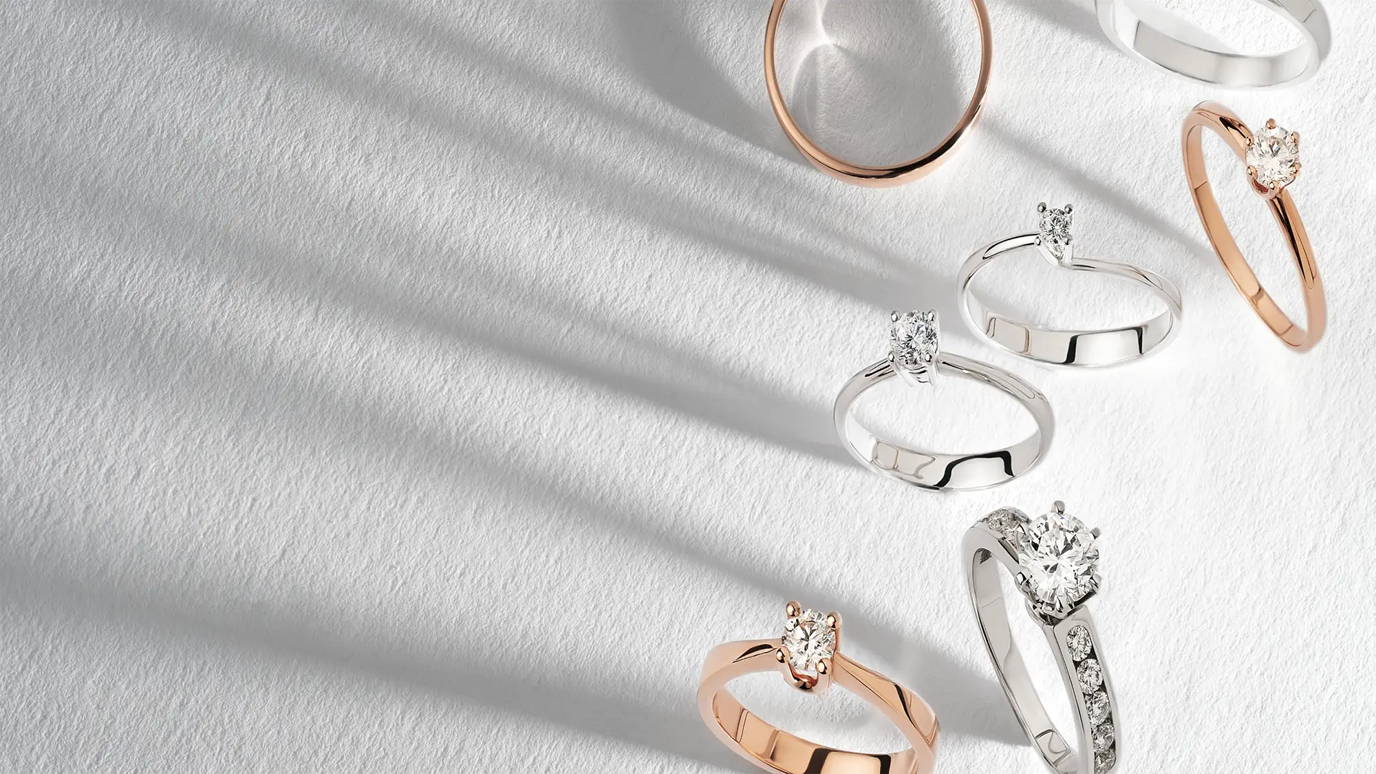 diamond rings with various settings in platinum and gold and shadows on a paper background