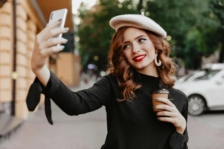 woman filming a selfie holding a coffee